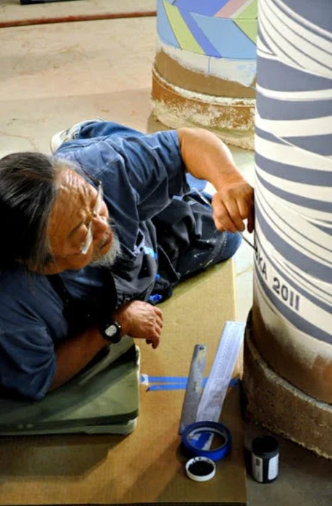 Ceramicist David Kuraoka working with clay in his studio, alongside large-scale pit-fired ceramic vessels.